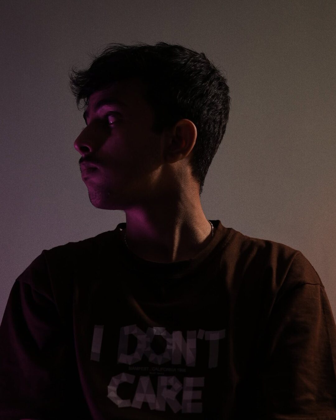 Portrait half-lost to shadow, 'I DON'T CARE' tee