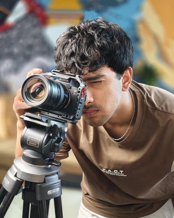 Aarohan behind a cinema camera on a tripod