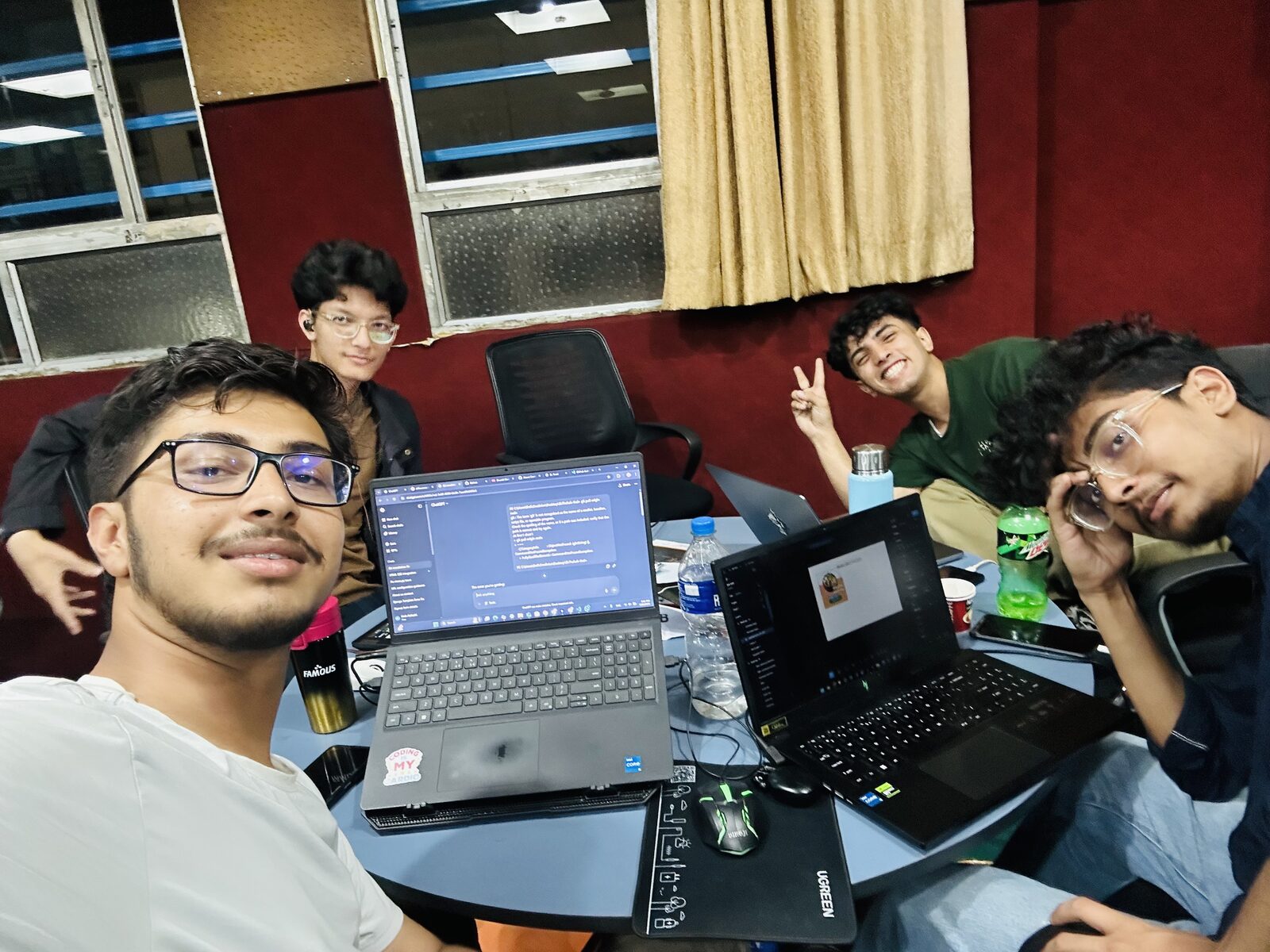 Friends crowded around a table of open laptops at night