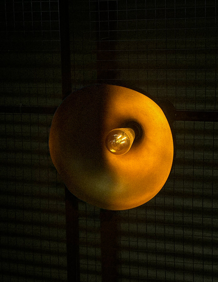 A round wall lamp glowing amber in a dark room