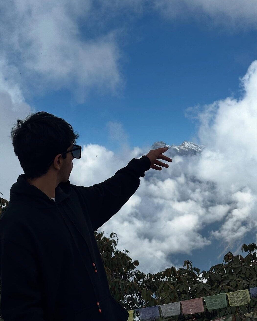 Aarohan reaching toward a Himalayan peak through the clouds