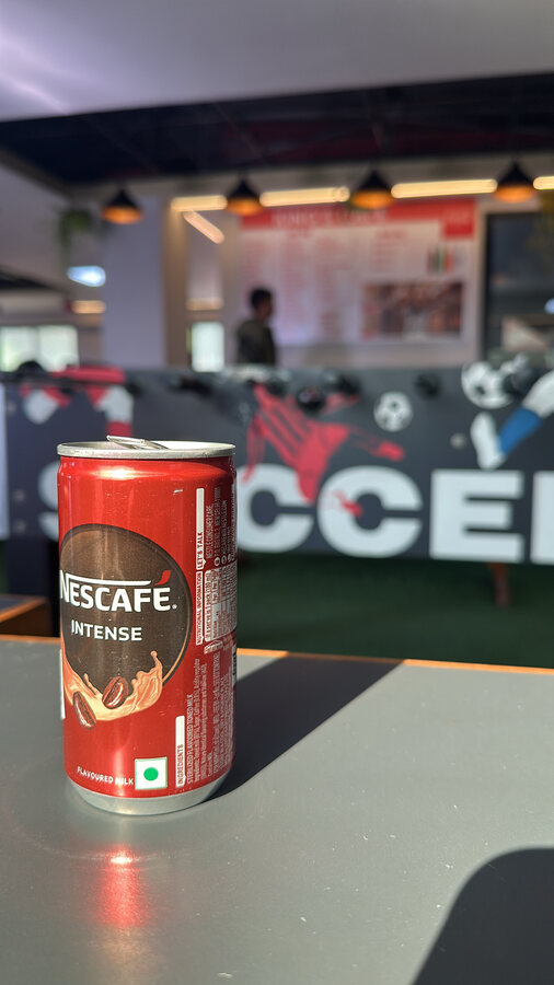 A coffee tin standing on an office floor by a turf five-a-side pitch