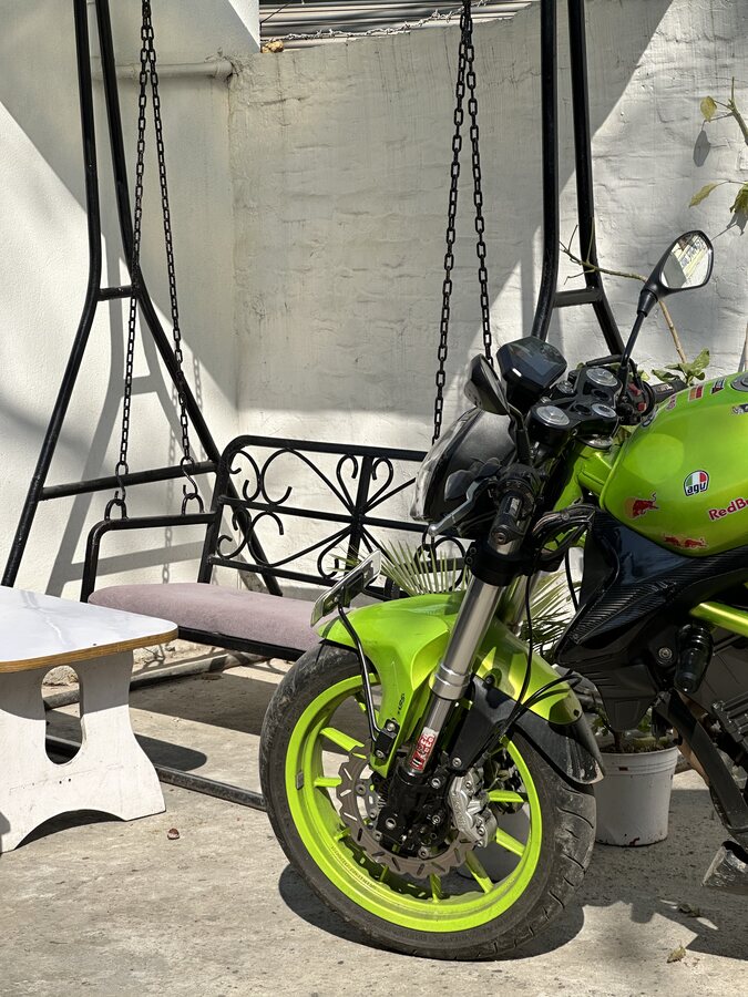 A lime green motorcycle parked beside a porch swing