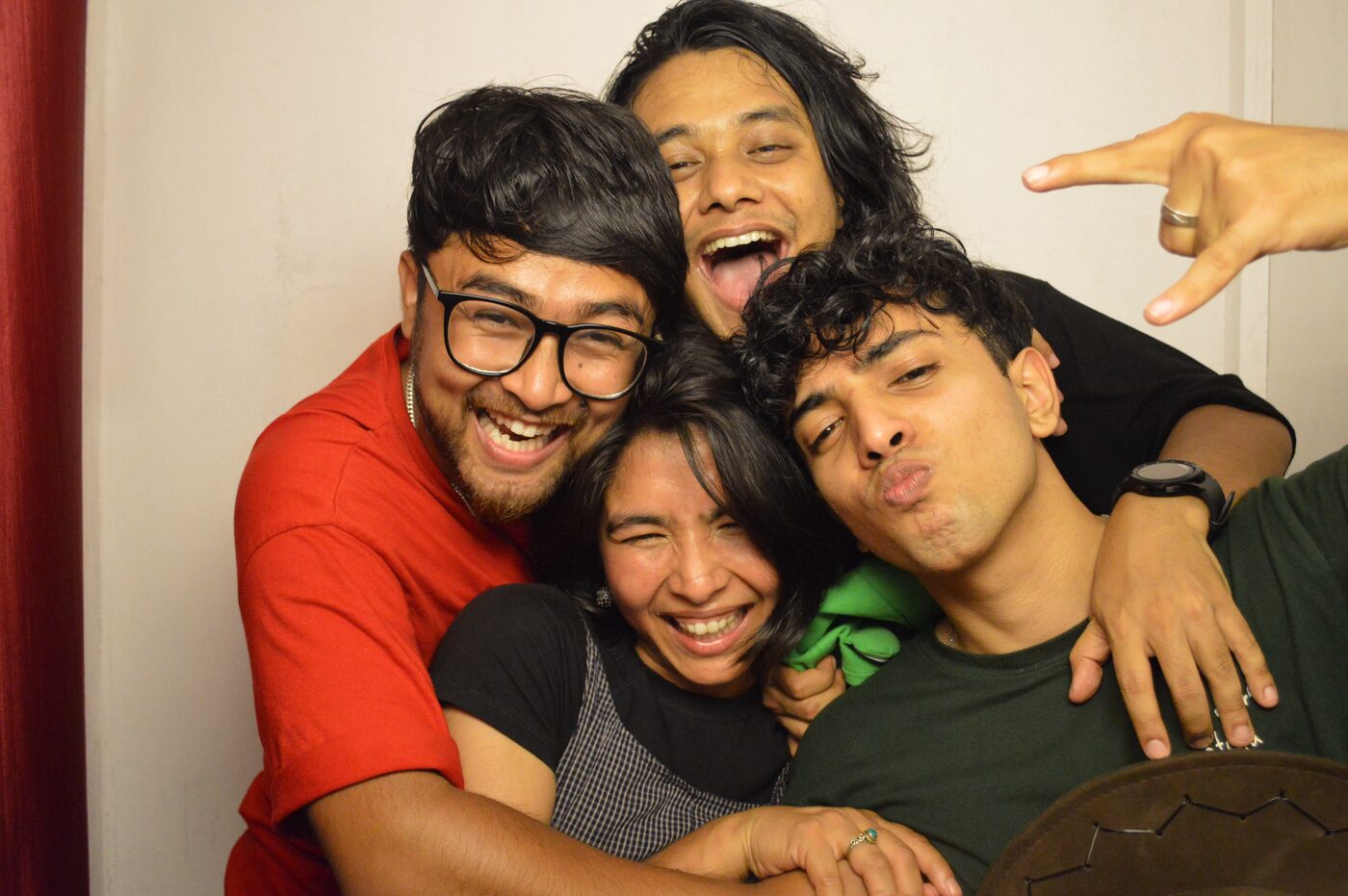 Four friends piled together laughing, shot on flash