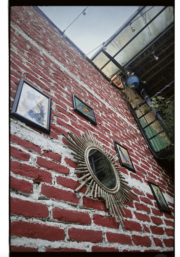 Sunburst mirror and small frames on a painted brick wall