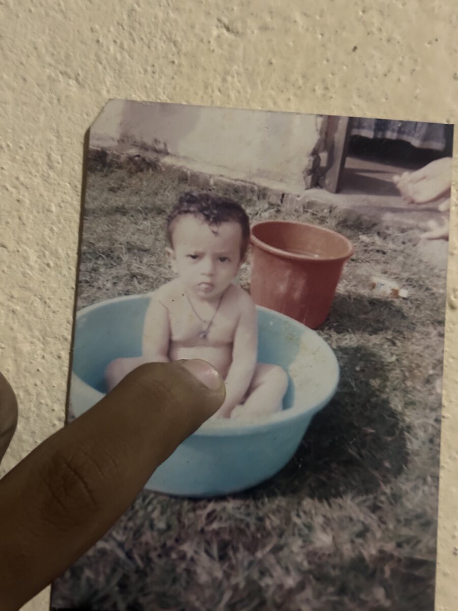 A hand holding an old print of a baby in a blue tub