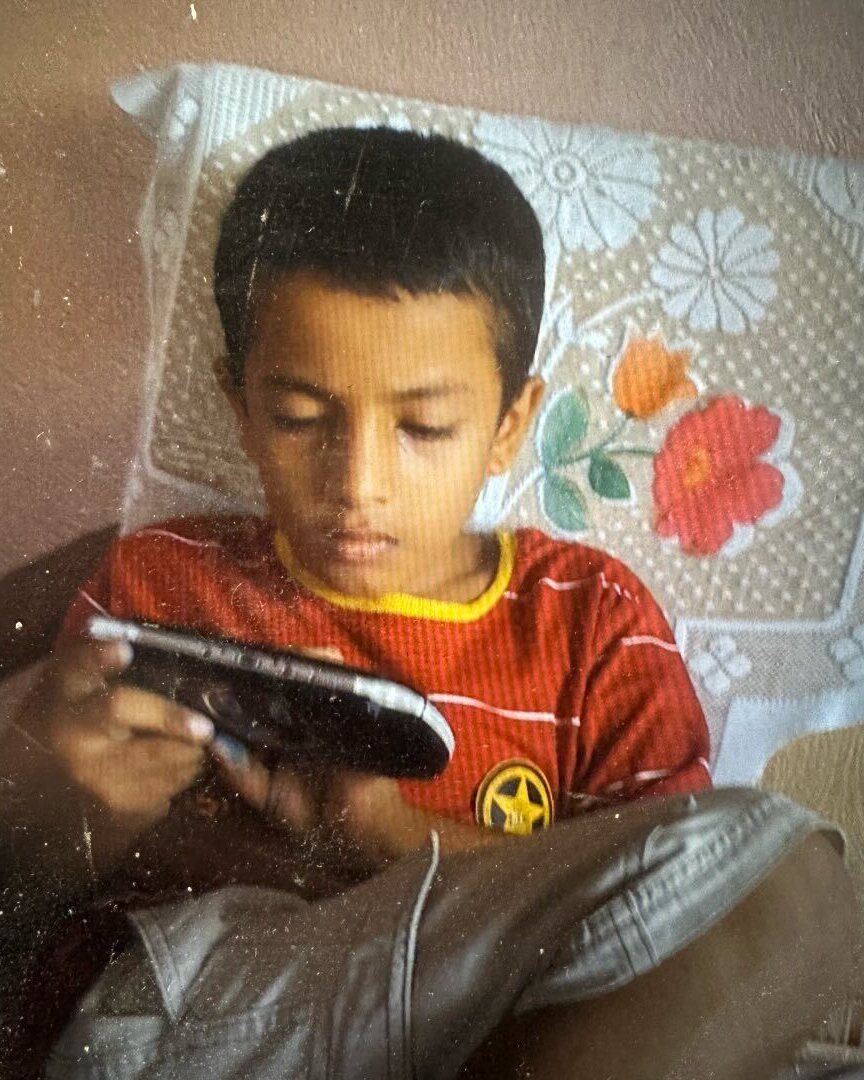 A boy on a bed, lost in a handheld console